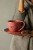 Kubek ceramiczny 400 ml malinowy handmade z talerzykiem, trzymany w dłoni