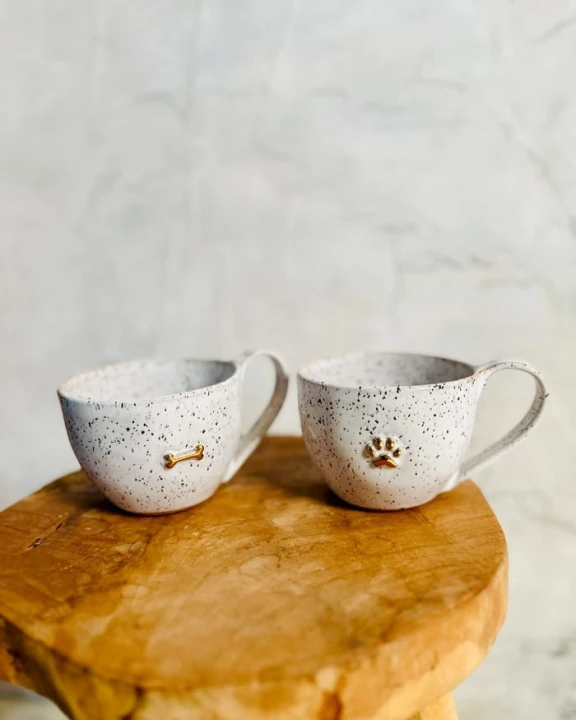 Kubek ceramiczny 400 ml stracciatella ze złotą łapką i złotą kostką stojący na stole